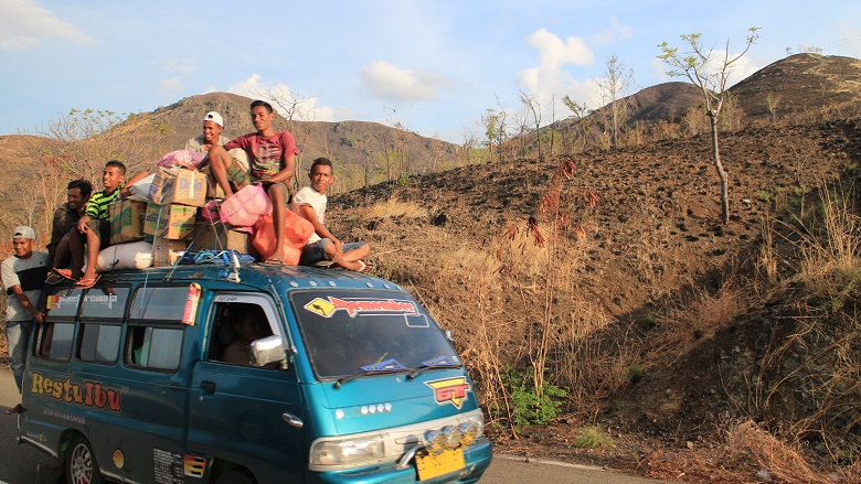 Hombres jóvenes viajan en la parte superior de una camioneta en Indonesia
