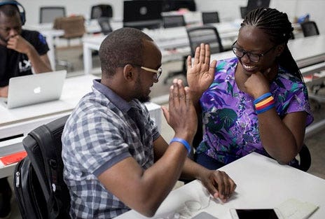 Two people high five while working on a laptop