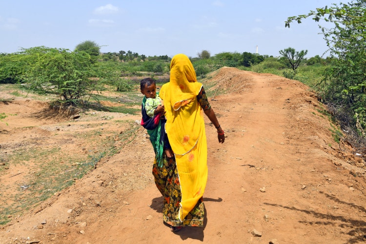 A woman walks down a path while holding a baby